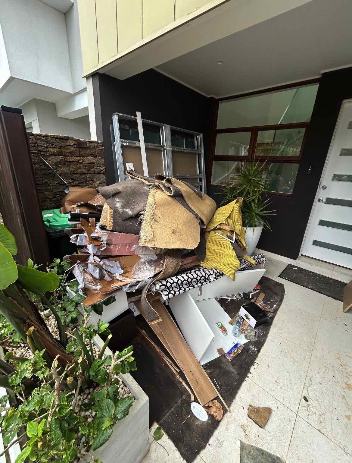 Courtyard rubbish removal before photo showing old carpet, cardboard, timber and mixed junk in Woollahra