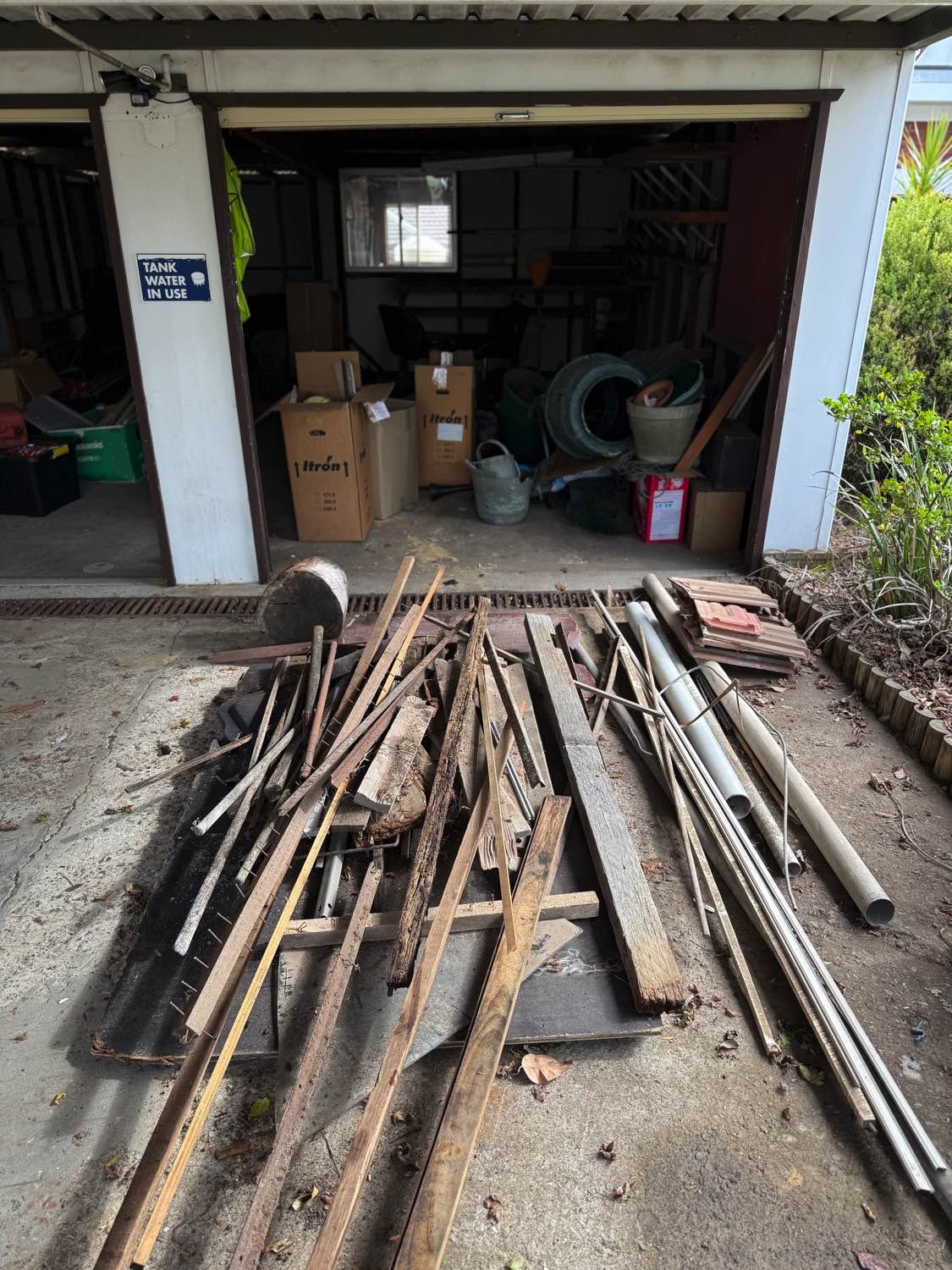 Garage junk removal before photo showing timber, pipes, boxes and unwanted clutter in Gymea