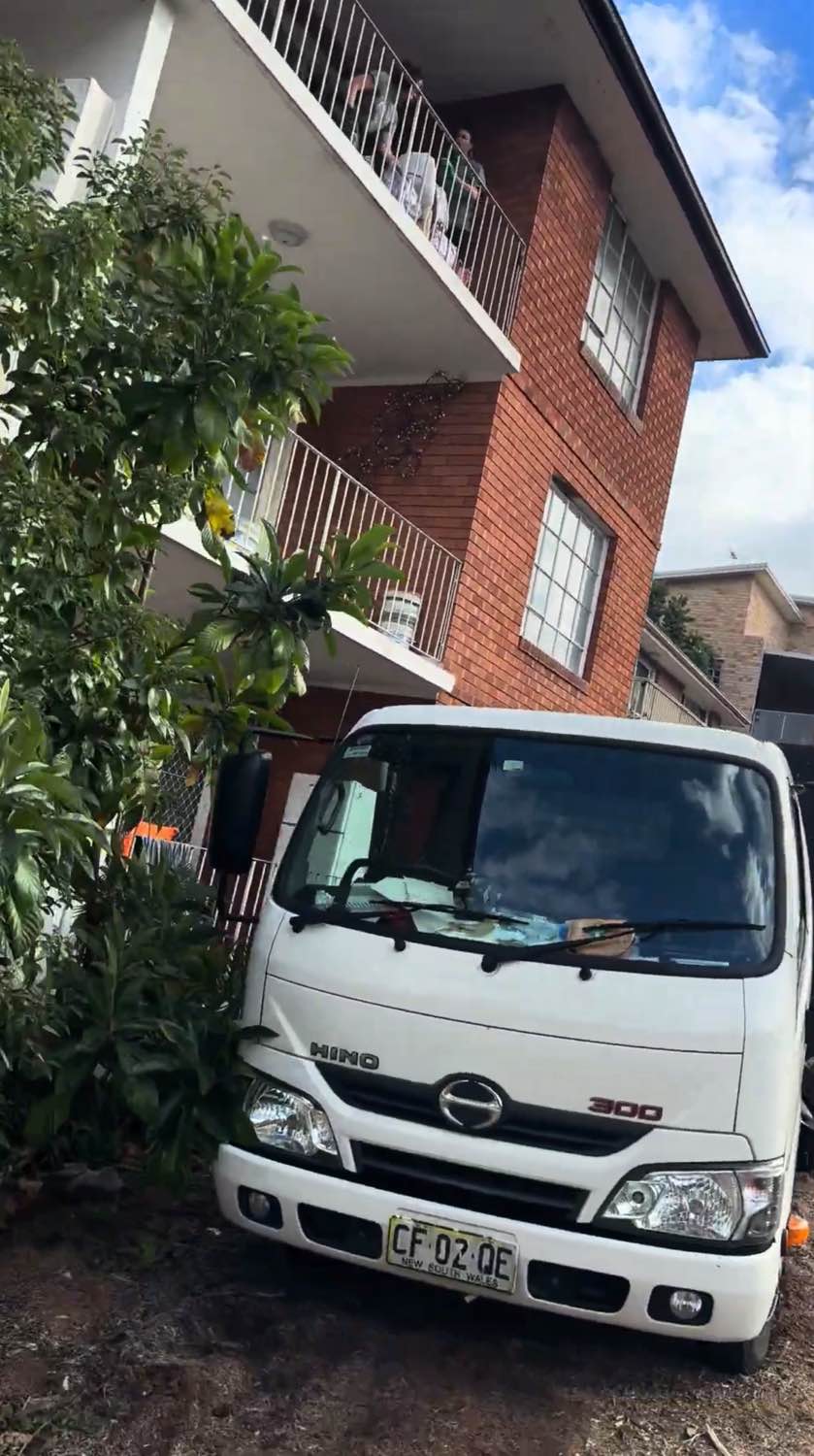 Rubbish removal truck positioned outside a three-storey brick apartment building in Randwick
